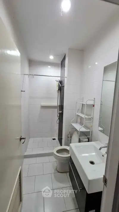 Modern bathroom with sleek fixtures and white tiles, featuring a shower and vanity unit.