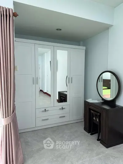 Elegant bedroom with white wardrobe and vanity set, perfect for modern living.
