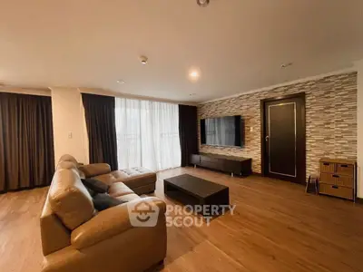 Spacious modern living room with elegant decor and large TV, featuring stylish wooden flooring.