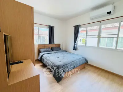 Cozy bedroom with modern furnishings and large windows offering natural light.