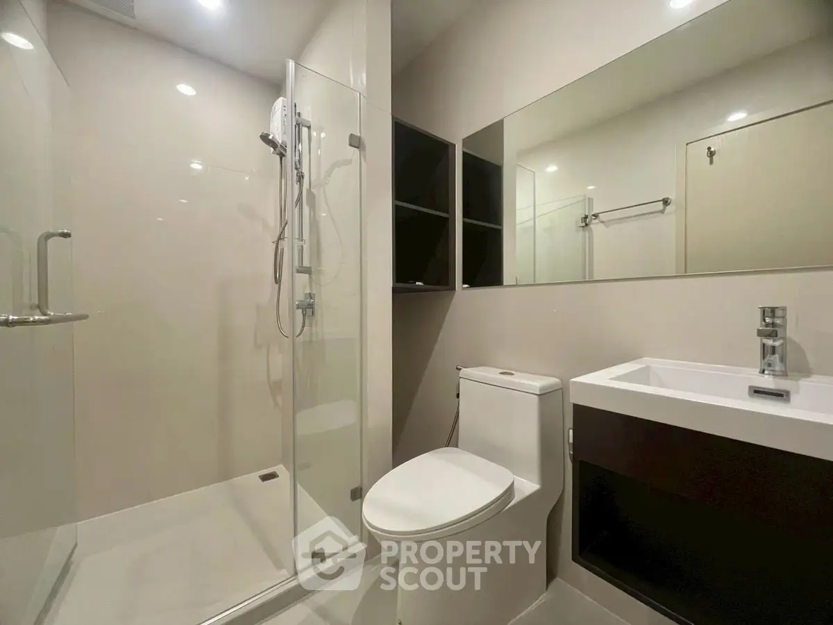 Modern bathroom with glass shower and sleek fixtures in contemporary apartment.