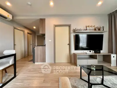 Modern living room with sleek furniture and open layout, featuring a wall-mounted TV and stylish decor.
