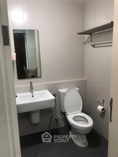 Modern bathroom with sleek fixtures and neutral tiles in a compact space.