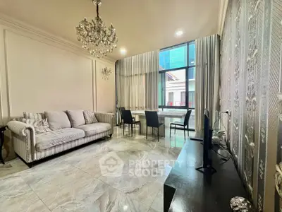 Elegant living room with chandelier, marble flooring, and large window offering city views.