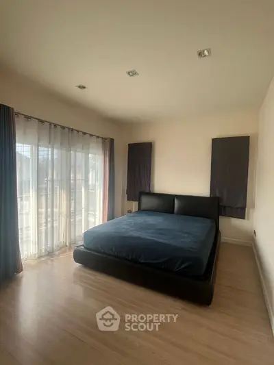 Spacious bedroom with large windows and modern decor, perfect for relaxation and comfort.