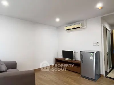 Modern living room with air conditioning and compact fridge, ideal for cozy urban living.