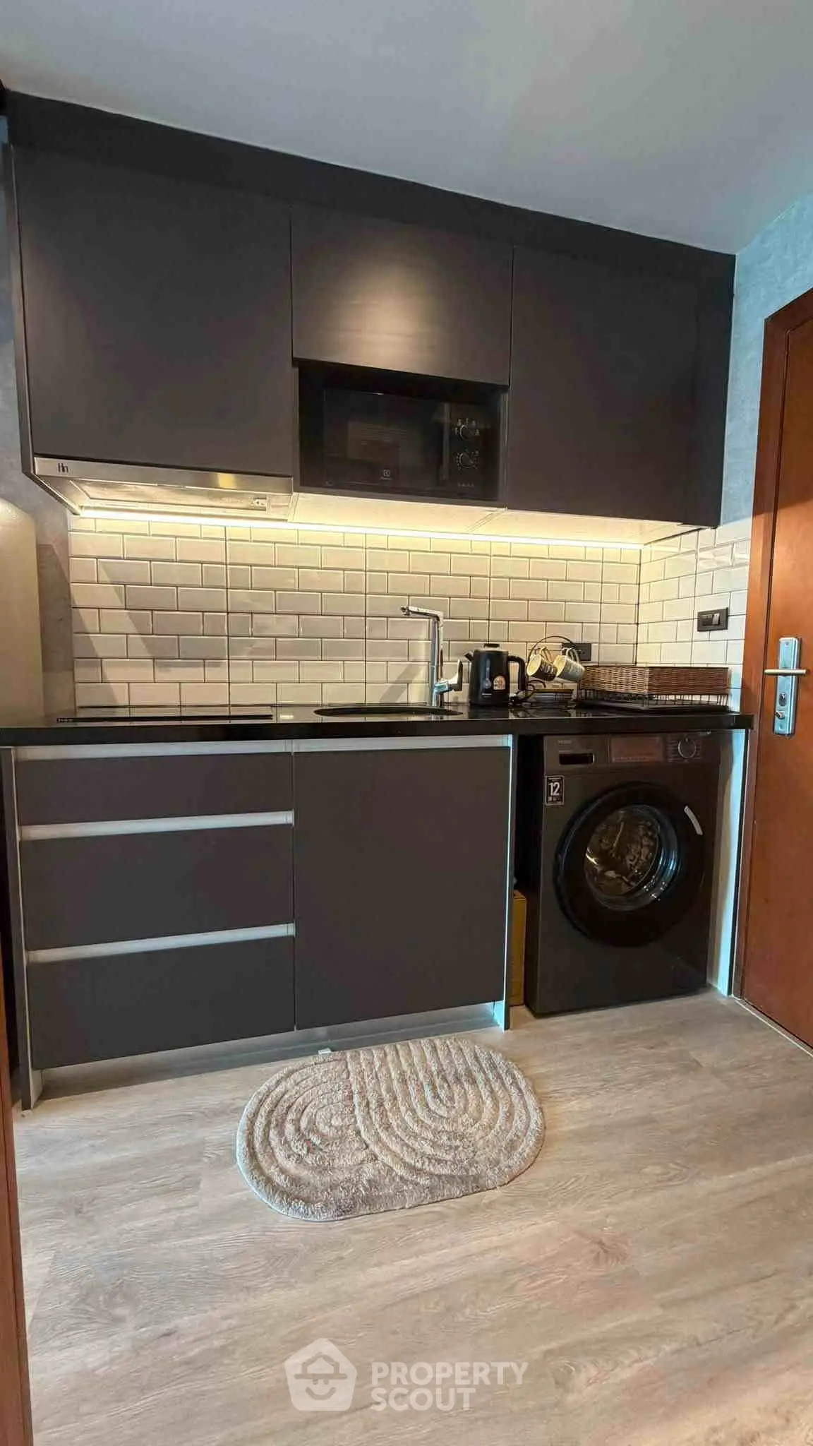 Modern compact kitchen with sleek cabinetry and integrated washing machine