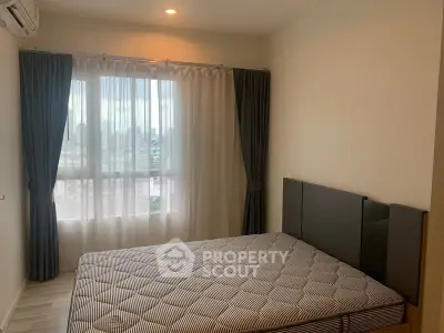 Cozy bedroom with large window and modern furnishings in a stylish apartment.