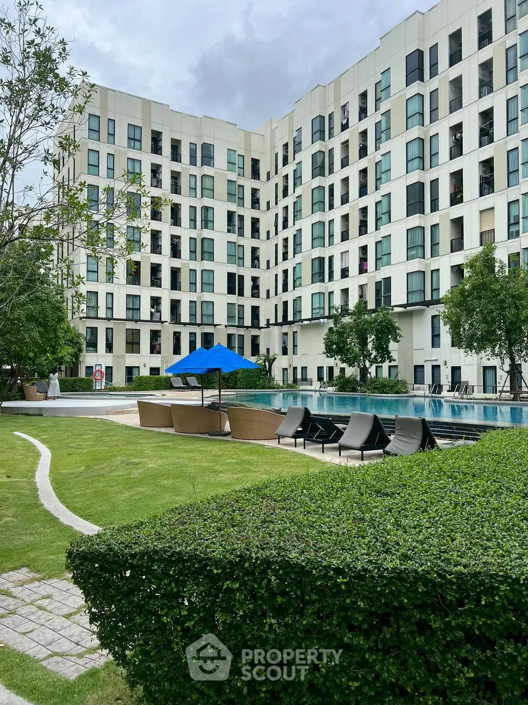 Modern apartment building with pool and lush garden area
