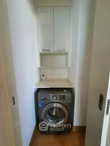 Compact laundry nook with modern washing machine and storage cabinets in a sleek apartment.