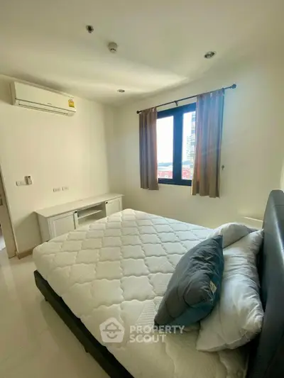 Bright bedroom with large window and modern furnishings in a cozy apartment.