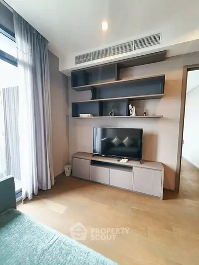Modern living room with stylish shelving and TV unit, featuring elegant wooden flooring and natural light.