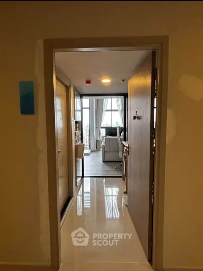 Spacious apartment entrance leading to a bright living room with large windows and elegant decor.