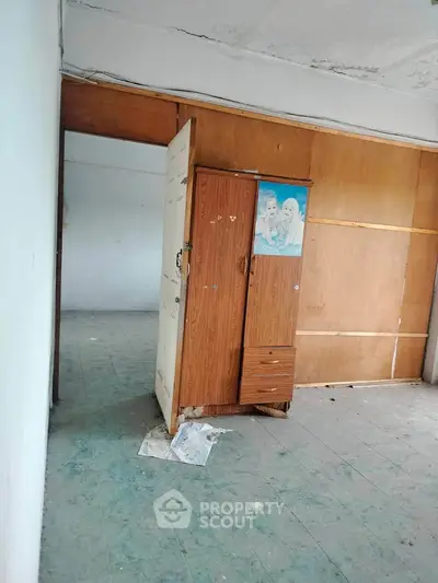 Spacious room with wooden wardrobe and tiled floor, ideal for renovation.