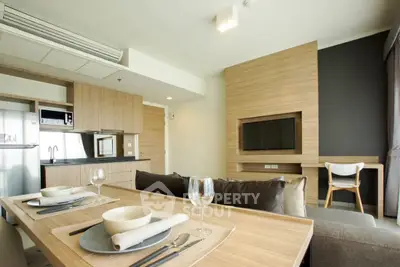 Modern open-plan living room with stylish kitchen and dining area, featuring sleek wooden finishes and contemporary decor.