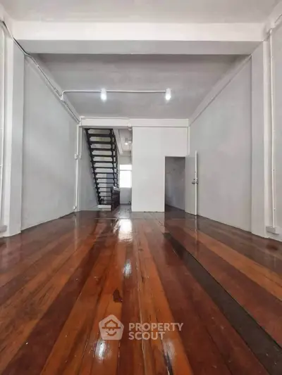 Spacious interior with polished wooden floors and staircase, ideal for modern living.