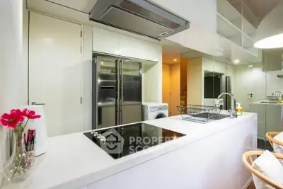 Modern kitchen with sleek appliances and open layout, featuring a washing machine and induction cooktop.
