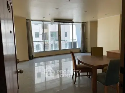 Spacious living room with large windows and dining area in modern apartment.