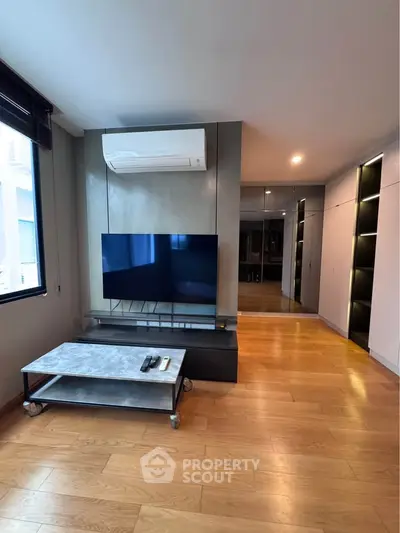 Modern living room with sleek TV setup and wooden flooring