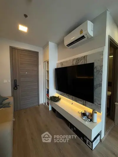 Modern living room with sleek TV setup and air conditioning in a stylish apartment.