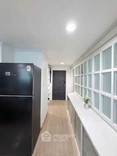 Modern kitchen with sleek black fridge and stylish cabinetry in a bright, airy space.