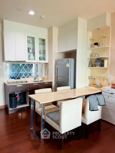 Modern kitchen with dining area, featuring sleek cabinetry and stainless steel appliances.