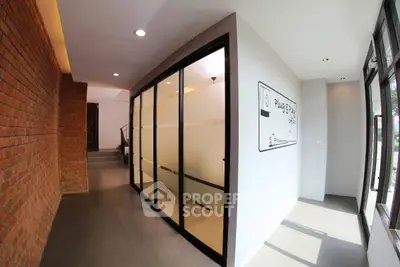 Modern office hallway with glass partitions and brick accent wall
