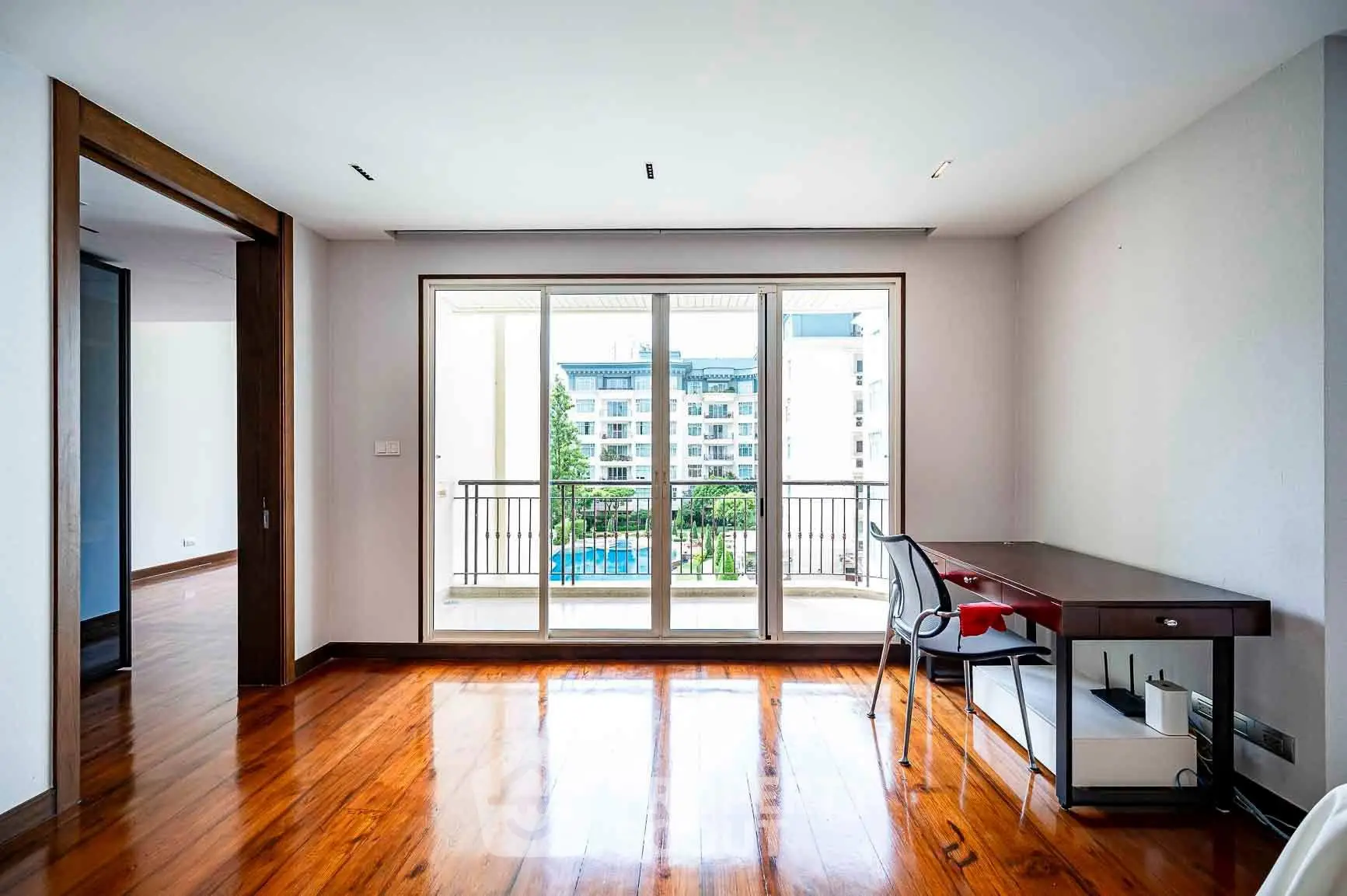 Spacious room with wooden floors and balcony view in modern apartment