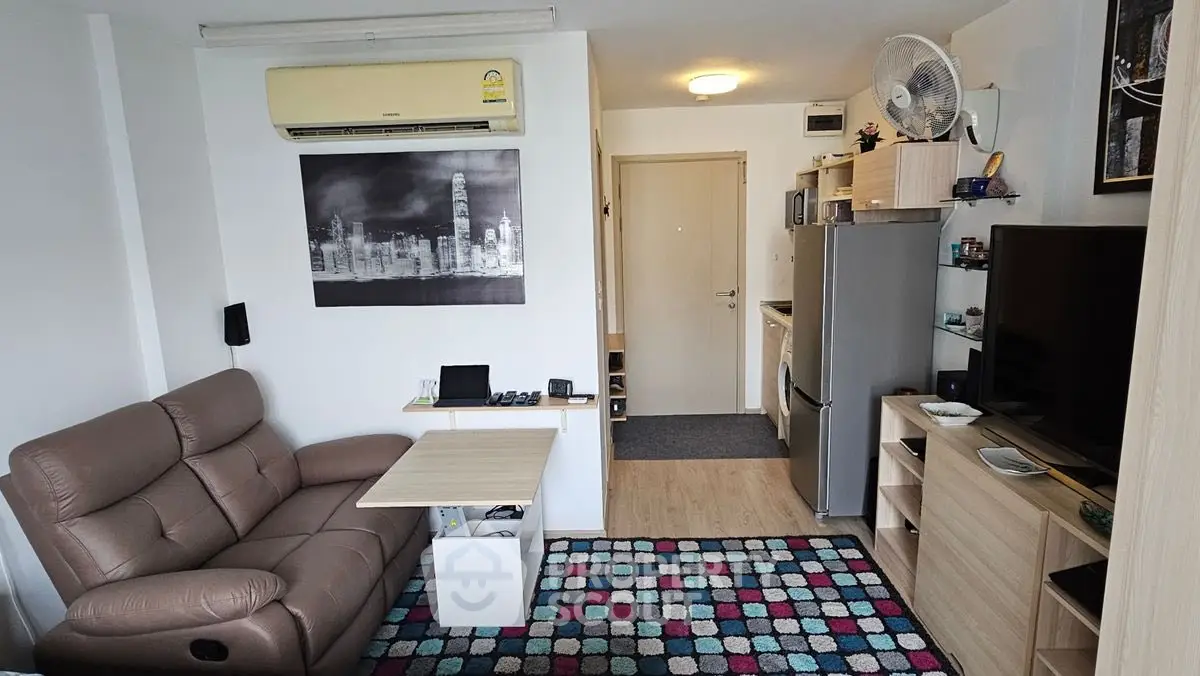 Cozy living room with modern decor and compact kitchen in open layout apartment.