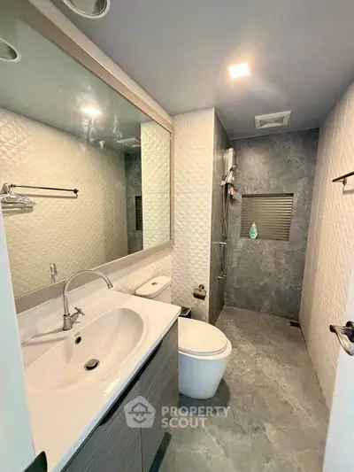Modern bathroom with sleek design, featuring a spacious shower and elegant fixtures.