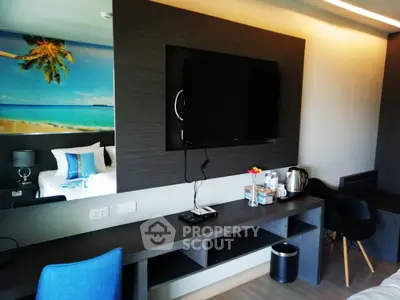 Modern hotel room with beach-themed decor and amenities, featuring a flat-screen TV and workspace.