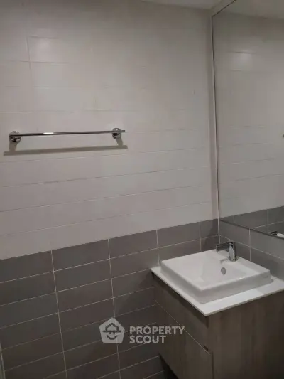 Modern bathroom with sleek sink and large mirror in contemporary apartment.