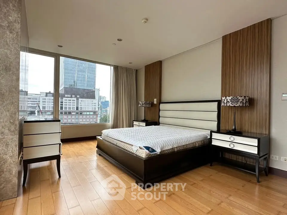Luxurious bedroom with modern furnishings and city view, featuring elegant wood flooring and large windows.