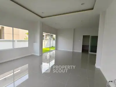 Spacious modern living room with large windows and glossy tiled floors.