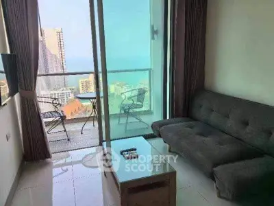 Modern living room with balcony offering stunning ocean view in high-rise apartment.