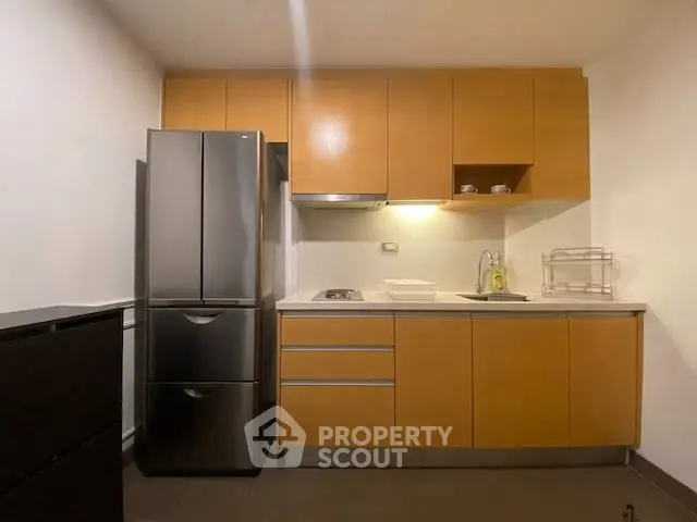 Modern kitchen with sleek cabinetry and stainless steel fridge in a compact layout.