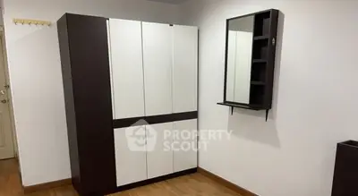 Modern bedroom with sleek wardrobe and wall-mounted mirror in minimalist design.
