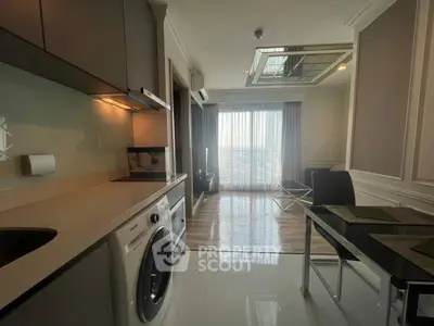 Modern apartment interior with kitchen and living area, featuring washing machine and large window view.