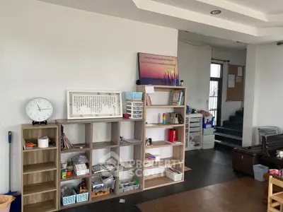 Spacious living room with modern shelving and natural light, ideal for family gatherings.