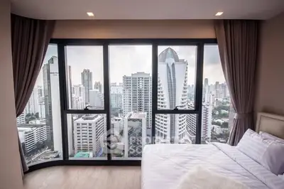 Luxurious bedroom with stunning city view and floor-to-ceiling windows in a high-rise apartment.