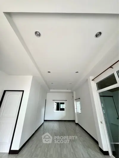 Spacious modern interior with sleek white walls and ceiling lights, perfect for customization.