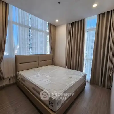 Spacious bedroom with large windows and modern decor in a high-rise apartment.