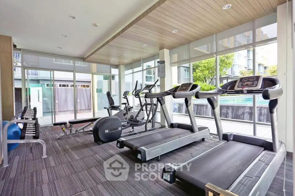Modern gym with state-of-the-art equipment and pool view in luxury apartment complex.