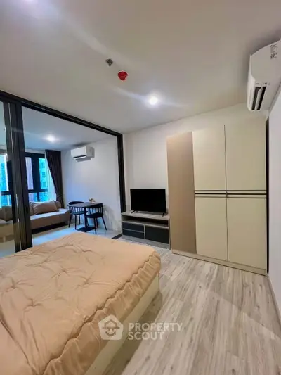 Modern bedroom with cozy decor and sliding glass doors leading to a stylish living area.