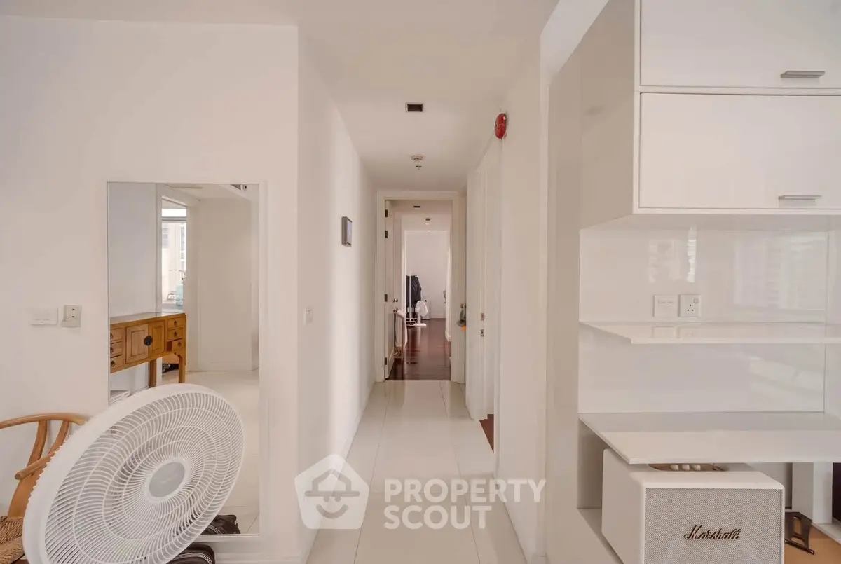Bright and spacious hallway in modern apartment with sleek white interiors and wooden accents.