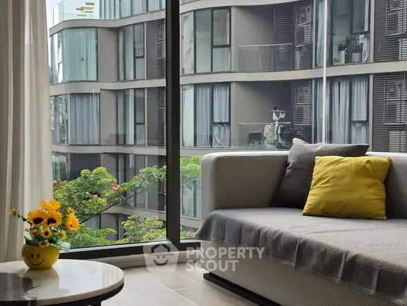 Modern living room with large window offering stunning view of contemporary building exterior.