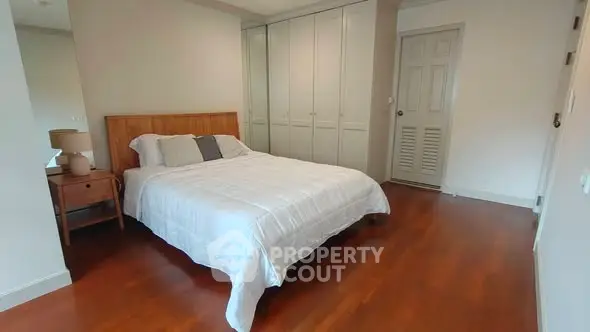 Spacious bedroom with wooden flooring and built-in wardrobe