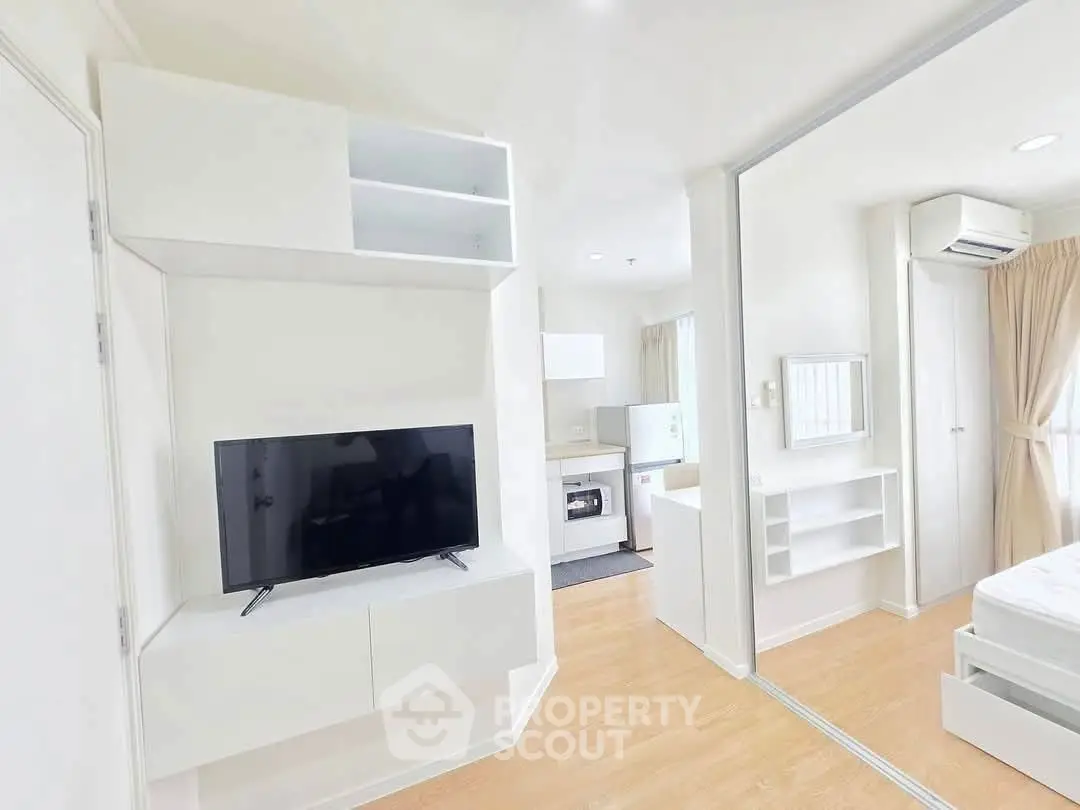 Modern apartment interior with open layout, featuring sleek white furniture and natural light.