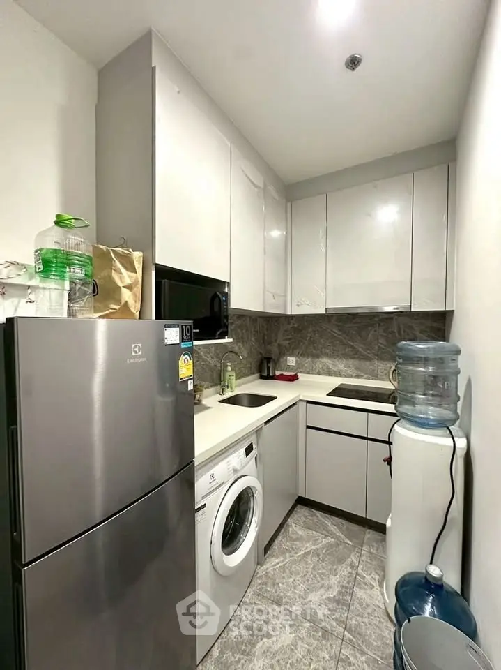 Modern compact kitchen with sleek cabinets, washing machine, and water dispenser in a stylish apartment.