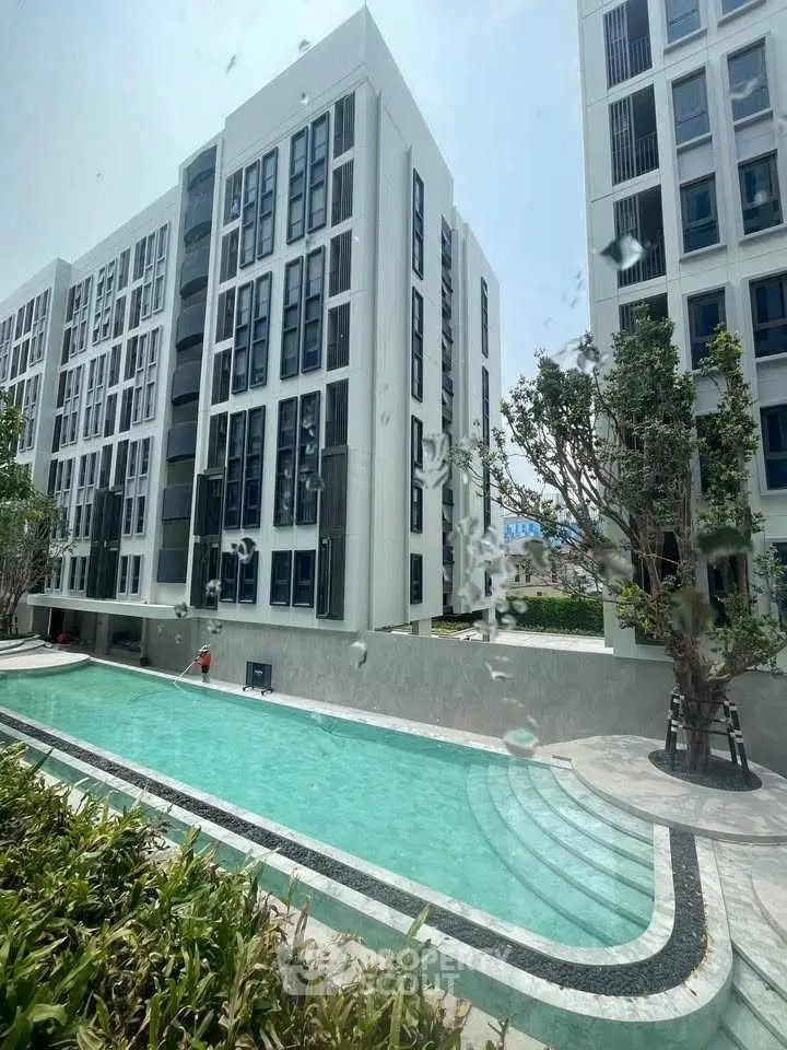 Modern apartment building with a pristine swimming pool and lush greenery.
